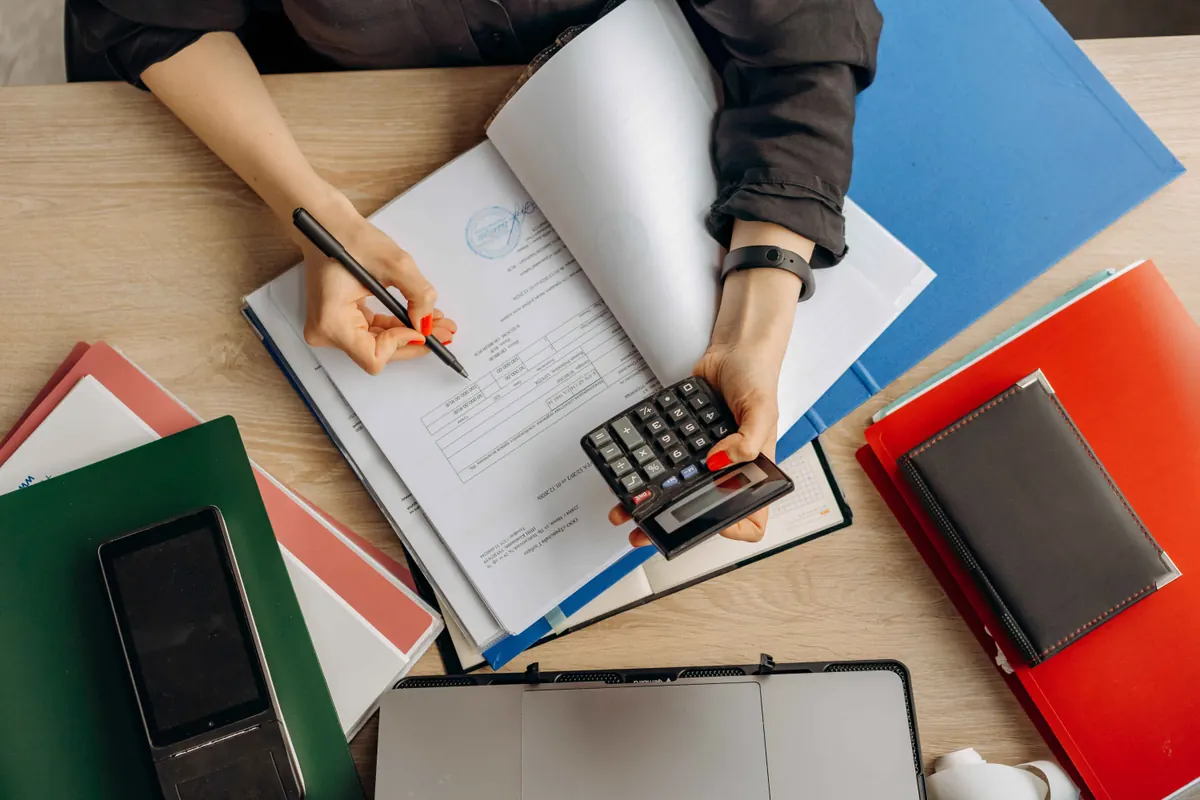 Personne vérifiant des documents à l’aide d’une calculatrice