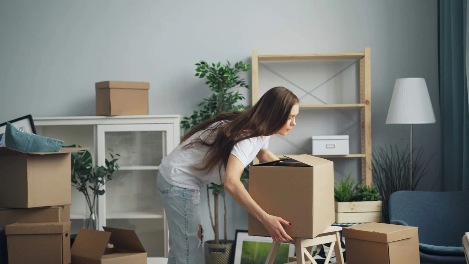 Woman moving a cardboard box in a room prepared for moving