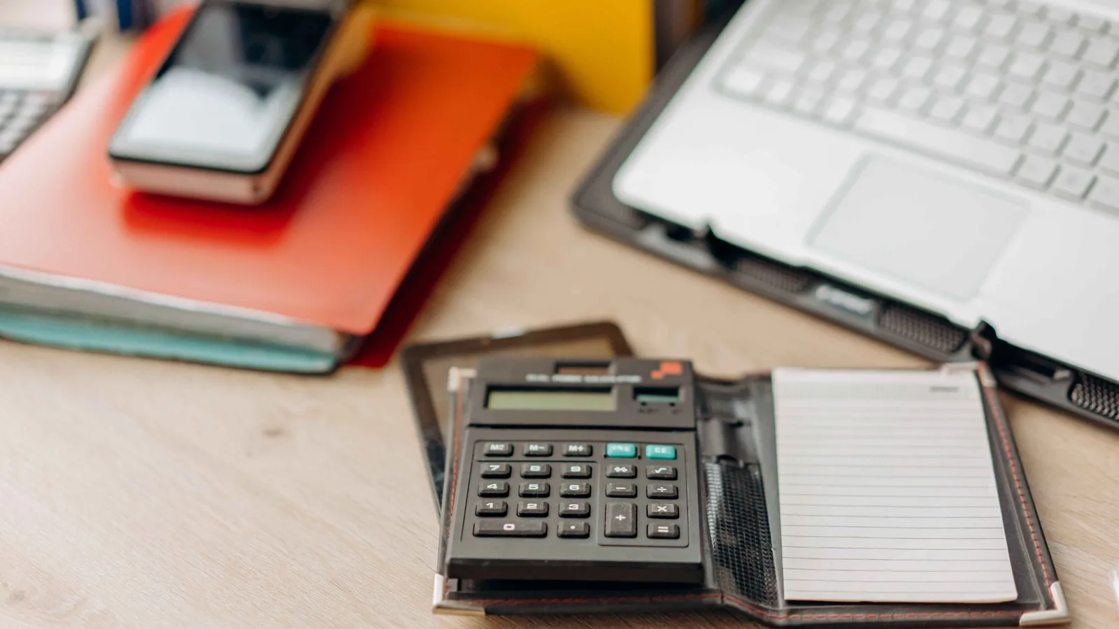 Calculator, notebook and laptop used to estimate professional packing costs