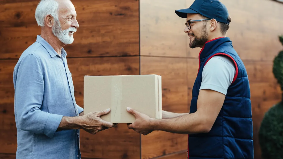 Professional mover handing a cardboard box to an older man