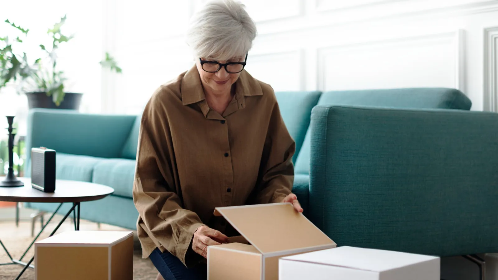 Older woman unpacking boxes in a bright living room