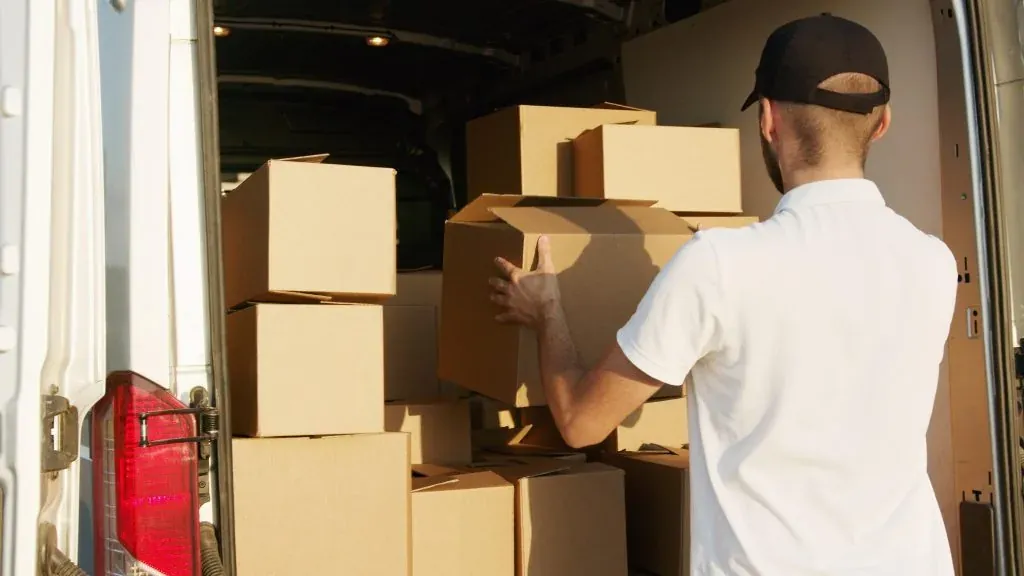 Homme chargeant des boîtes de carton à l’arrière d’une camionnette