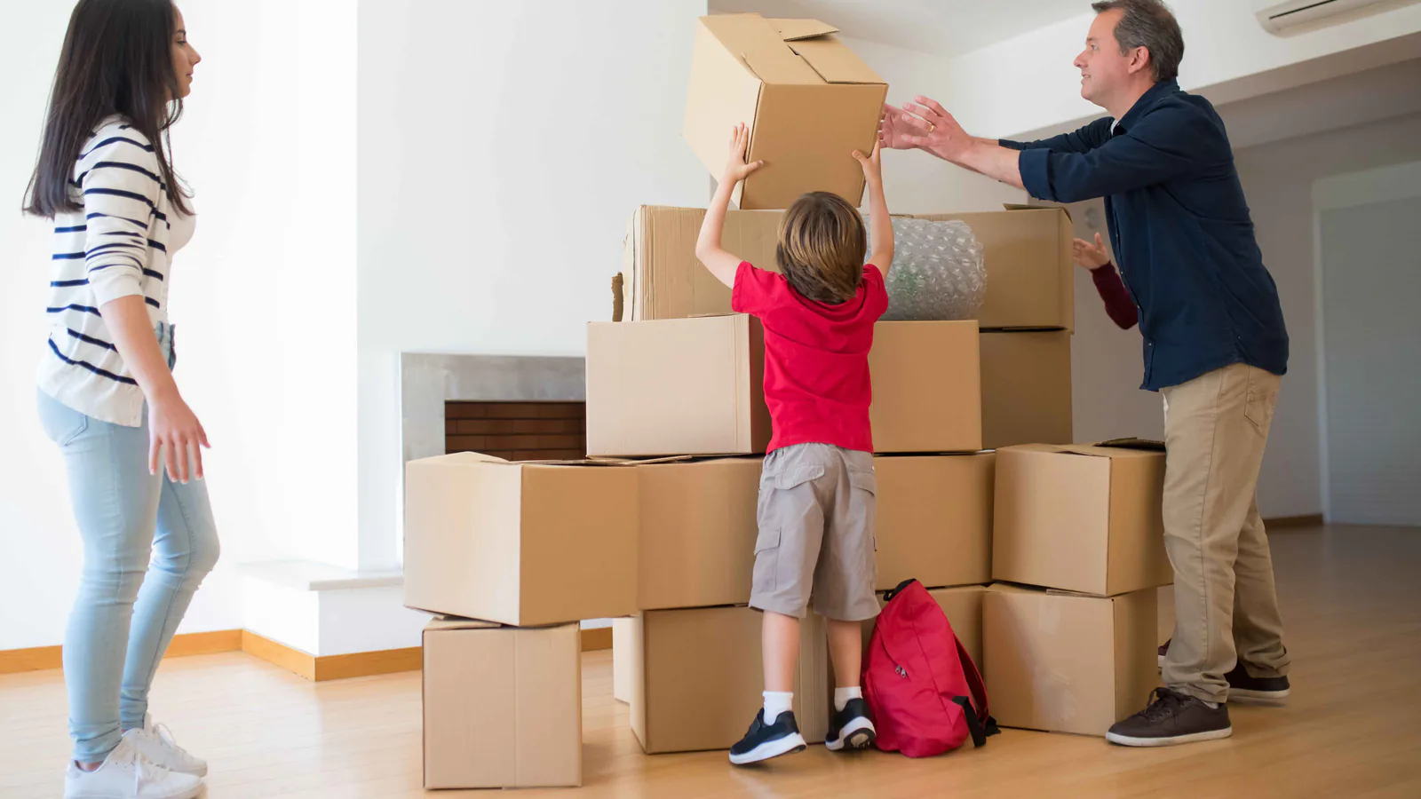 Parents and child arranging cardboard boxes together during a family move