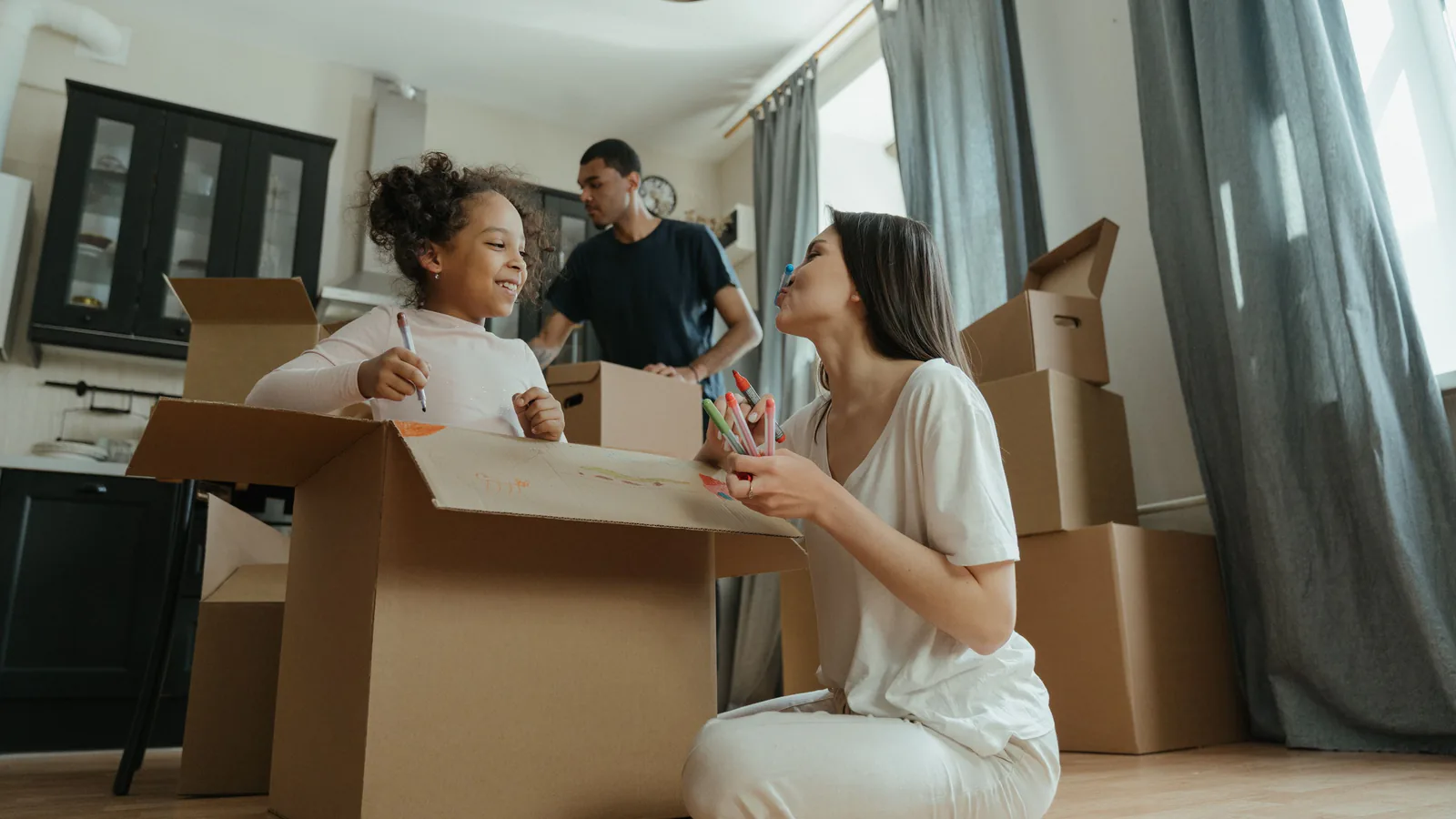 Parent and child decorating a cardboard box while packing for a family move