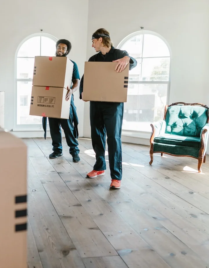 Professional movers carrying boxes in a bright home