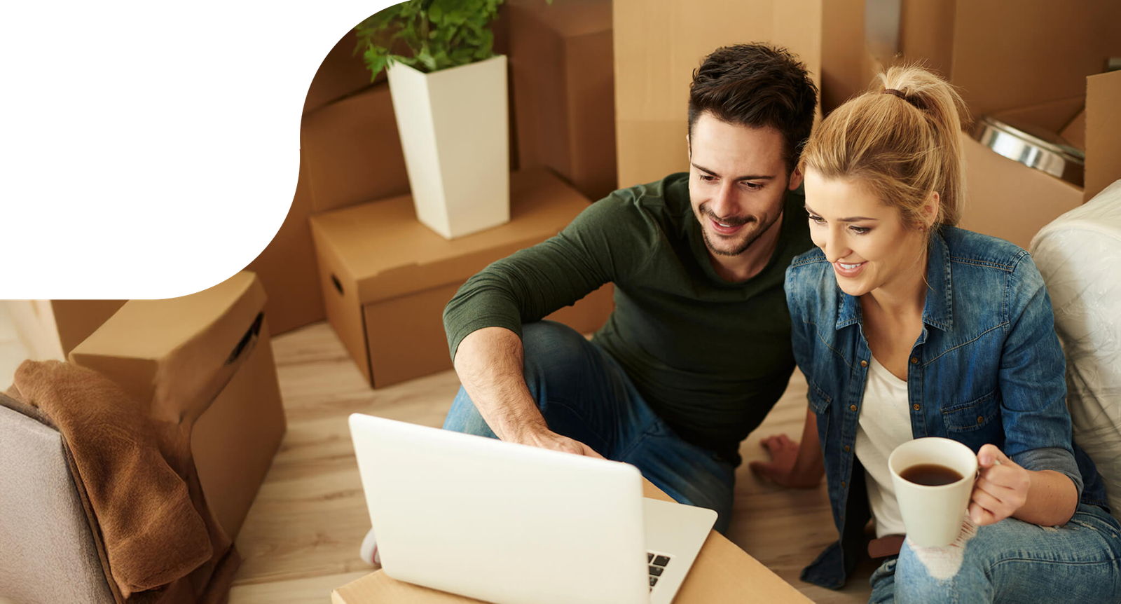 Couple comparing movers on a laptop while surrounded by moving boxes