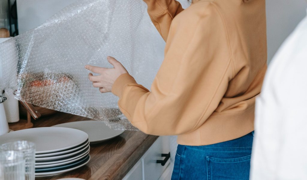How to Pack Dishes for Moving- Our Best Packing Tips girl packing dishes for moving